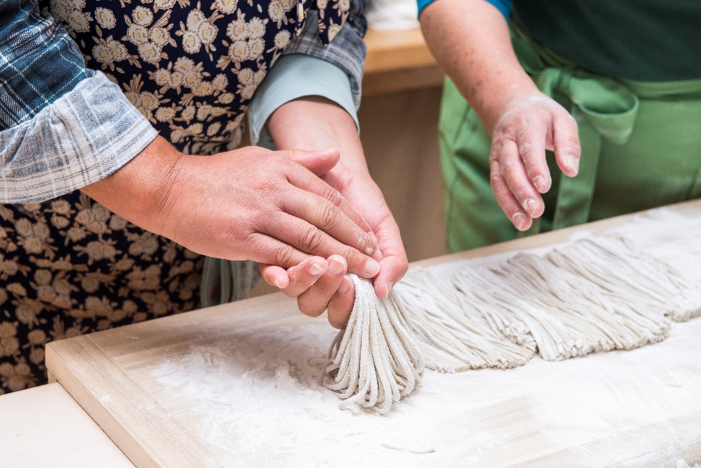 A traveler learning the traditional art of rolling soba dough at the Bungotakada Soba Dojo, Oita.